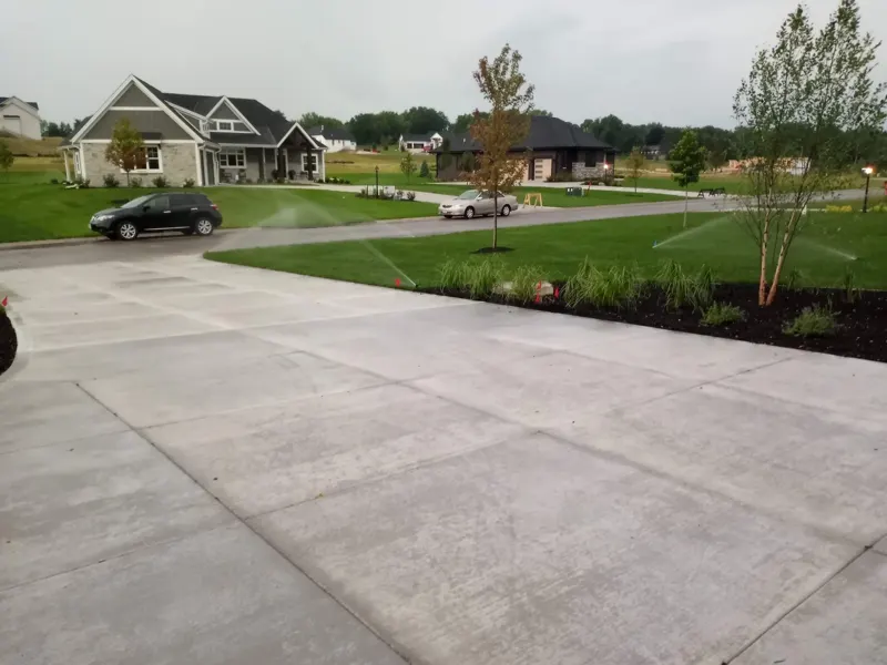 Sprinklers covering lawn beside a new concrete driveway